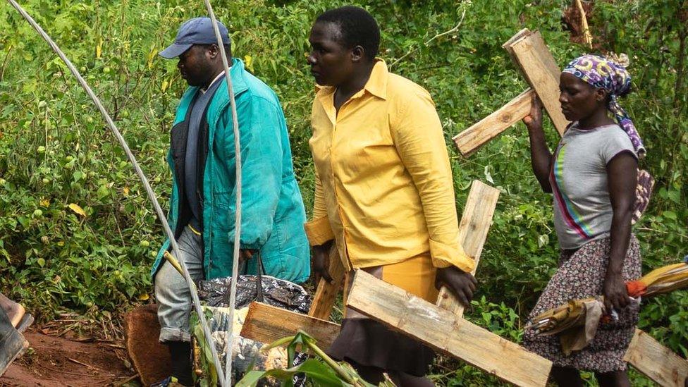 People carrying crosses in Chimanami at bodies are buried after Cyclone Idai