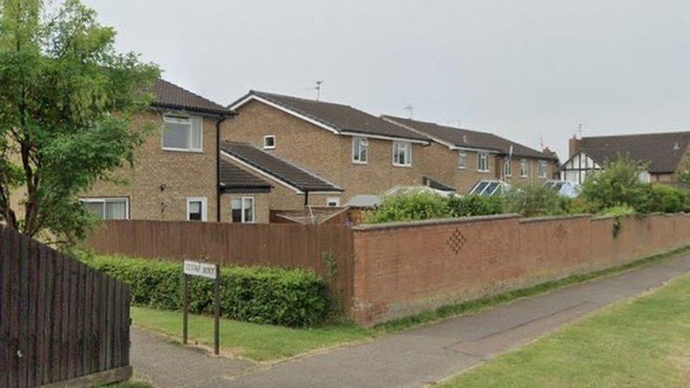 Modern houses behind a brick wall. A footpath to the left is signed "Lovap Way"