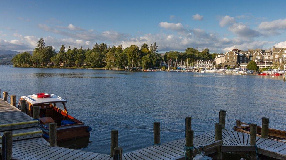 Bowness-on-Windermere harbour with wooden boat and pier in the foreground