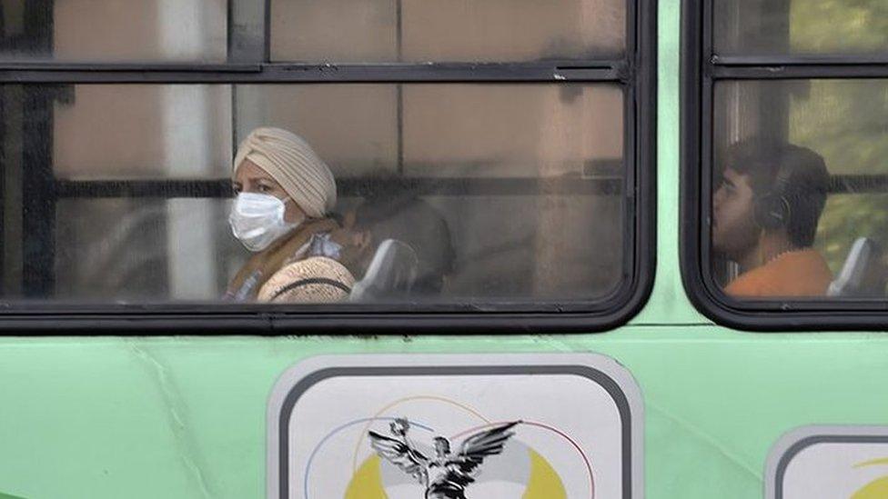 A woman wears a surgical mask while using the electrical transport system in smog-covered Mexico City on 3 May 2016