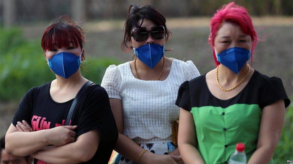 Chinese people wearing masks look on at a street after a huge explosion rocked the port city of Tianjin, China, 13 August 2015