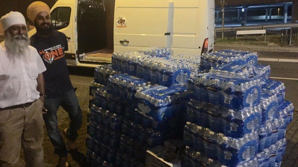 Two men with pallets of water