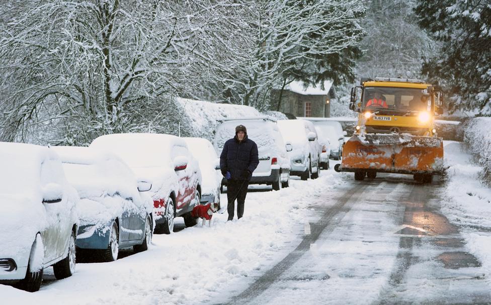 A man walks his dog through snow-covered roads in Allenheads, Northumberland, 21 January 2021