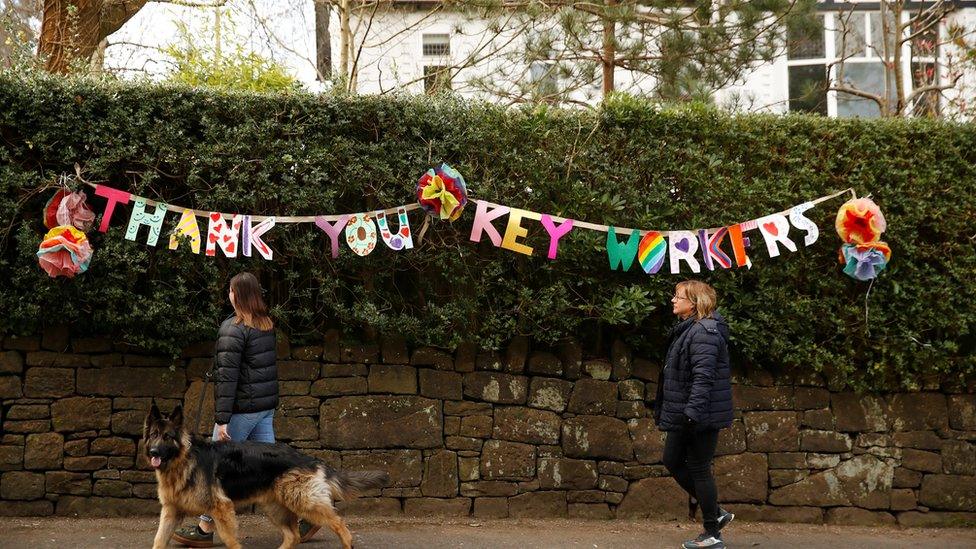 People walk past a banner reading "Thank you key workers", as the spread of the coronavirus disease (COVID-19) continues, Manchester