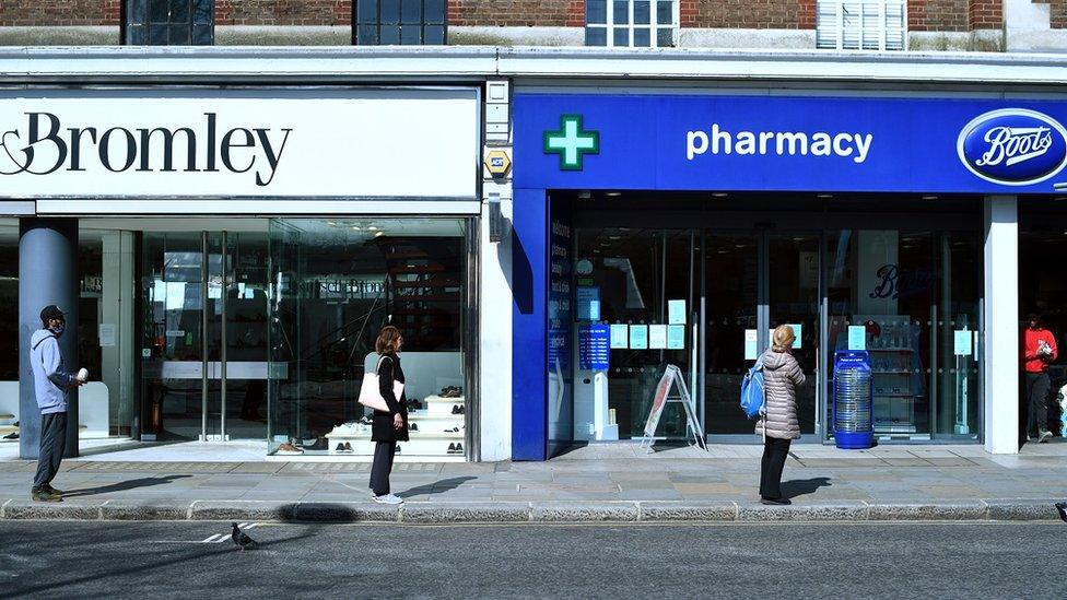 People waiting outside a Boots pharmacy in London