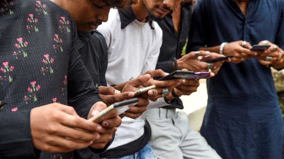 Youngsters watch videos on video-sharing app TikTok on their mobile phones