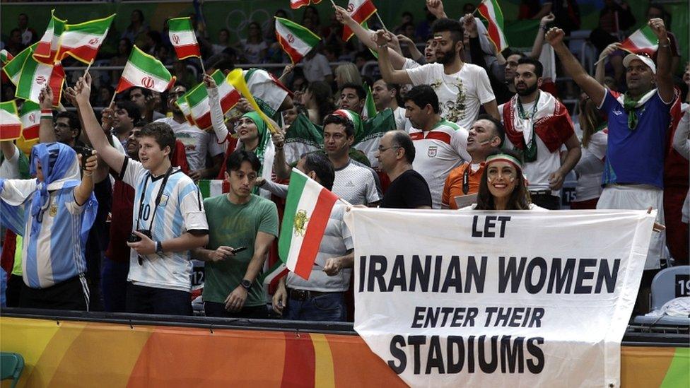 Darya Safai (R) holds a protest sign at the 2016 Summer Olympics in Rio de Janeiro, Brazil (13 August 2016)