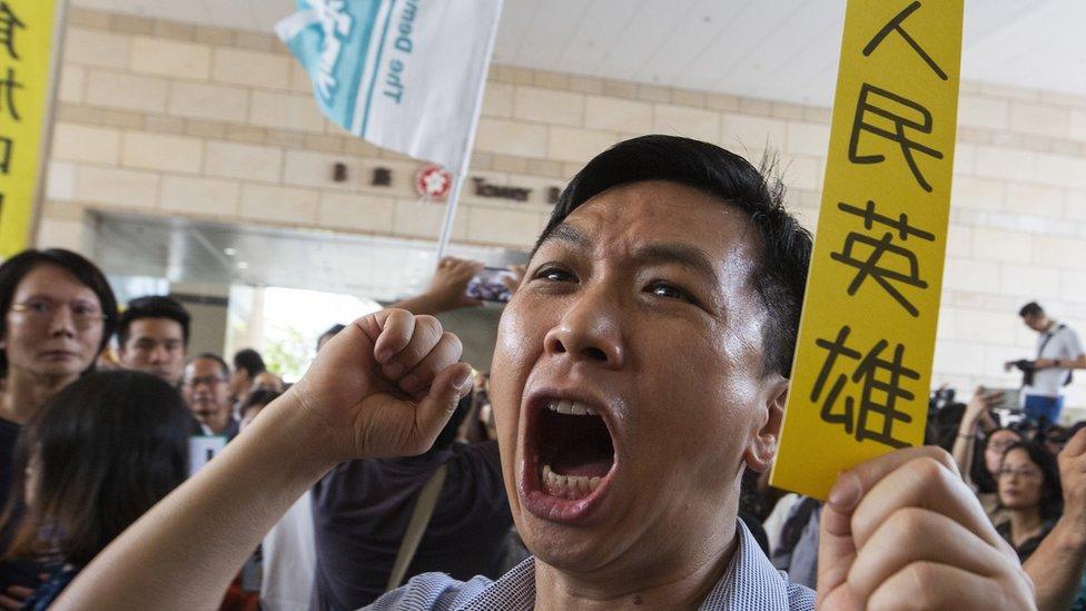 A pro-Democracy activist holds a piece of yellow paper with a slogan in Chinese saying "People"s Hero"