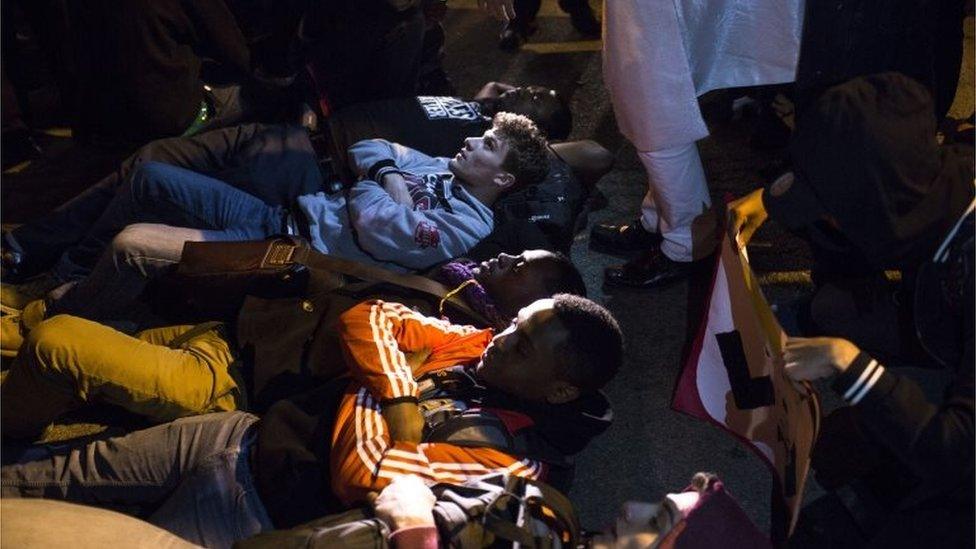 Protesters lay down in the path of a car attempting to exit the University of Illinois at Chicago Pavilion where Republican presidential candidate Donald Trump cancelled a campaign