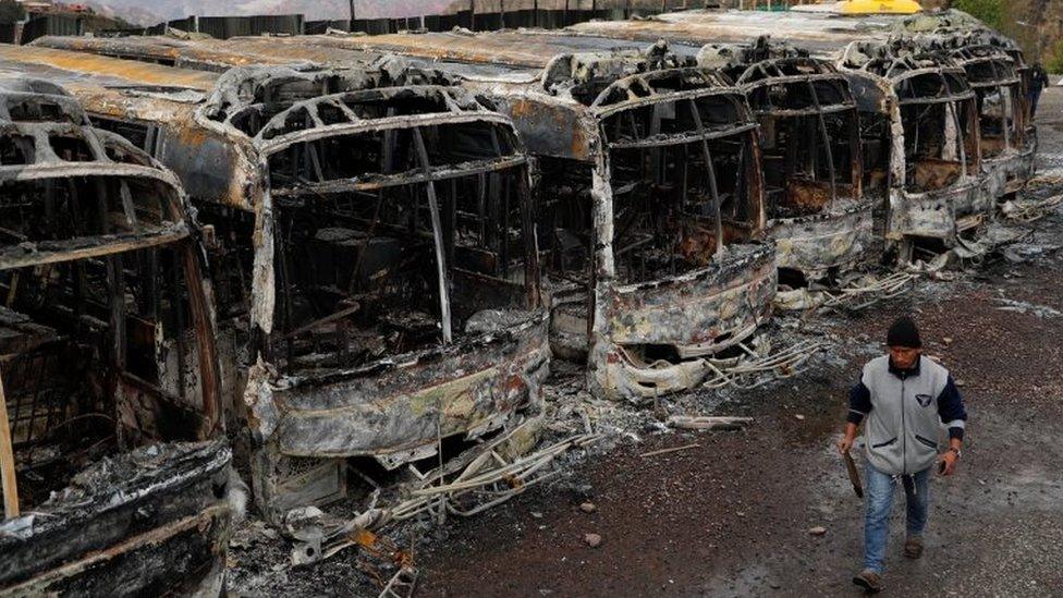 man walks past buses burned during a protest after Bolivia's President Evo Morales announced on Sunday that he was resigning, in La Paz, Bolivia November 11, 2019.