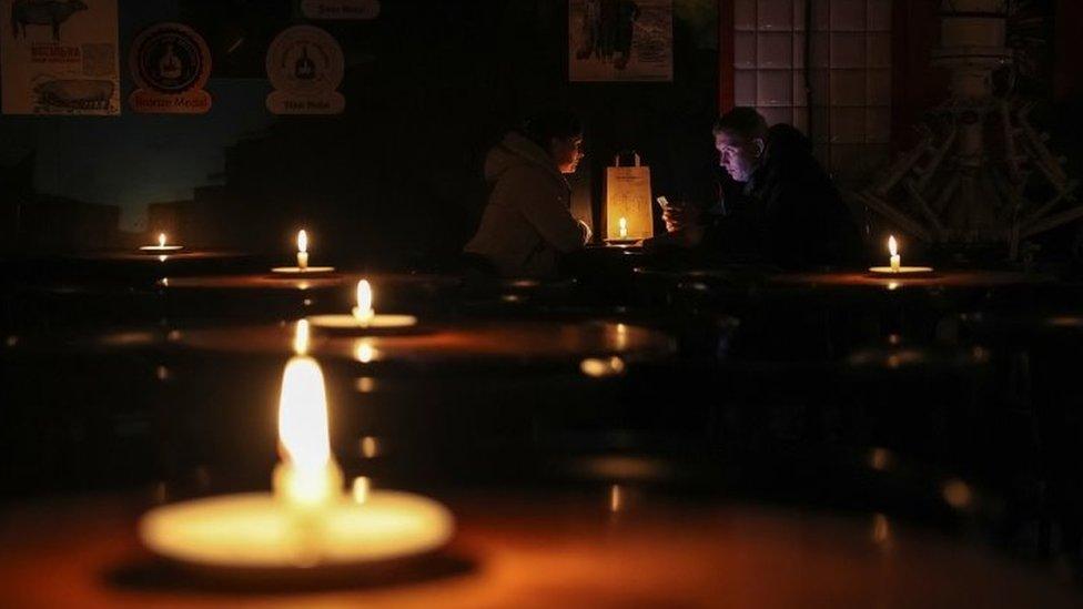 People sit a pub lit with candles in Lviv, western Ukraine. Photo: 24 November 2022