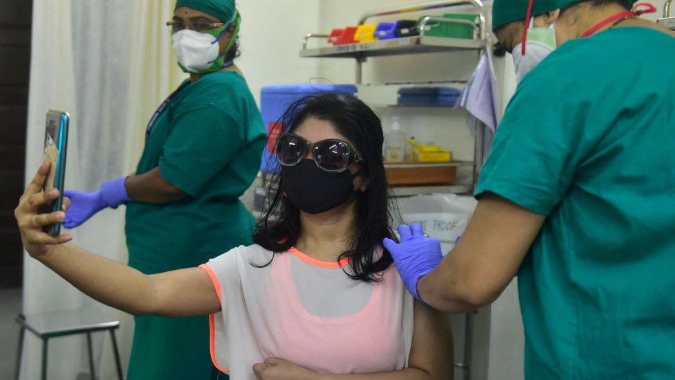 A woman taking a selfie while getting a jab