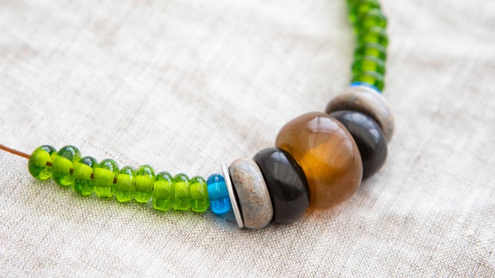 Replica of a Bronze Age necklace of green and blue glass beads, black and grey beads and an amber bead