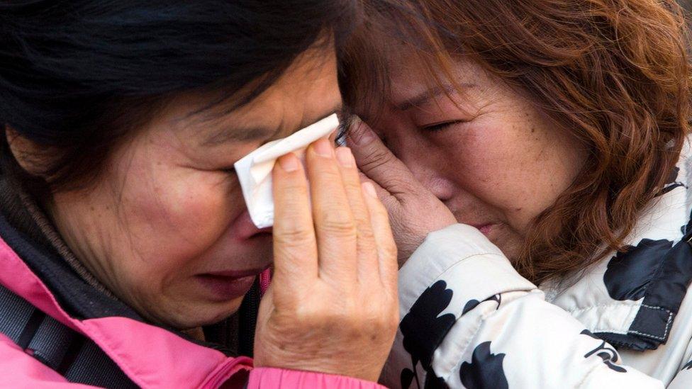 Relatives of passengers who were on board the Malaysia Airlines Flight 370 cry outside after filing lawsuit in Beijing