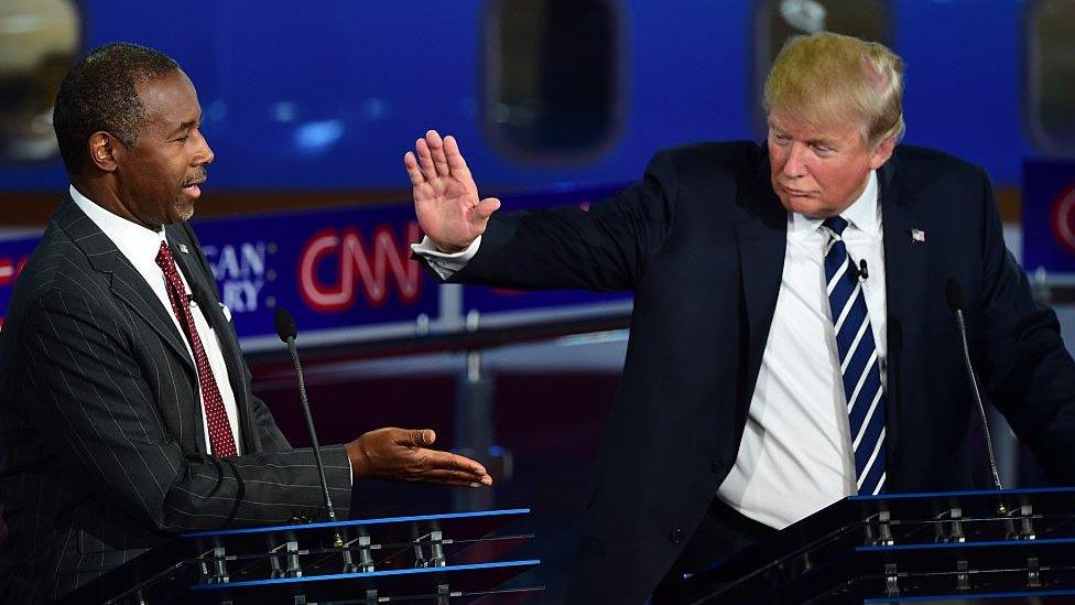 Donald Trump and Ben Carson slap hands at a presidential debate.