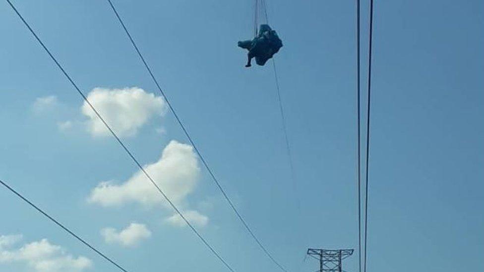 A paraglider is seen suspended from a wire in Táchira state