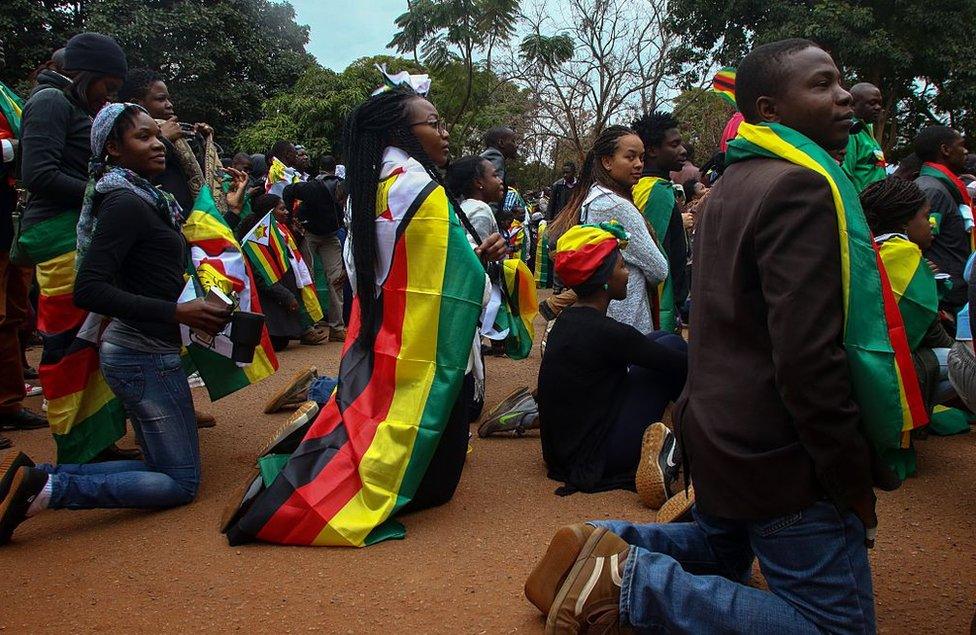 Supporters of 'ThisFlag campaign' kneel for prayer at the entrance of the Harare magistrate's court where pastor Evan Mawarire appeared on charges of inciting public violence following his arrest ahead of a planned mass job stayaway on July 13, 2016.