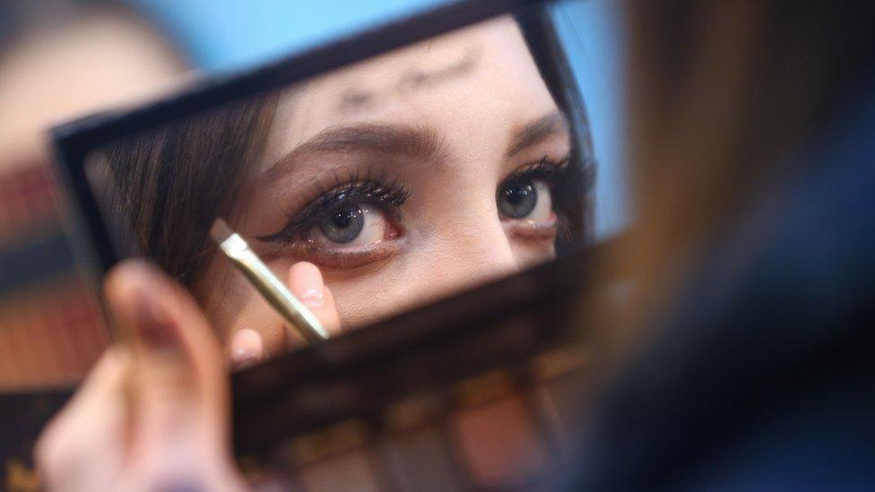 A woman applies eye makeup