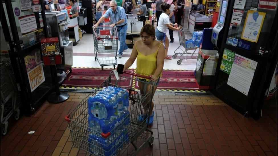 A woman purchases bottled water from a local grocery store as Tropical Storm Dorian approaches in Cabo Rojo, Puerto Rico