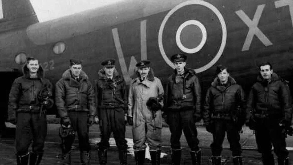 Black and white picture of the seven airmen next to their plane