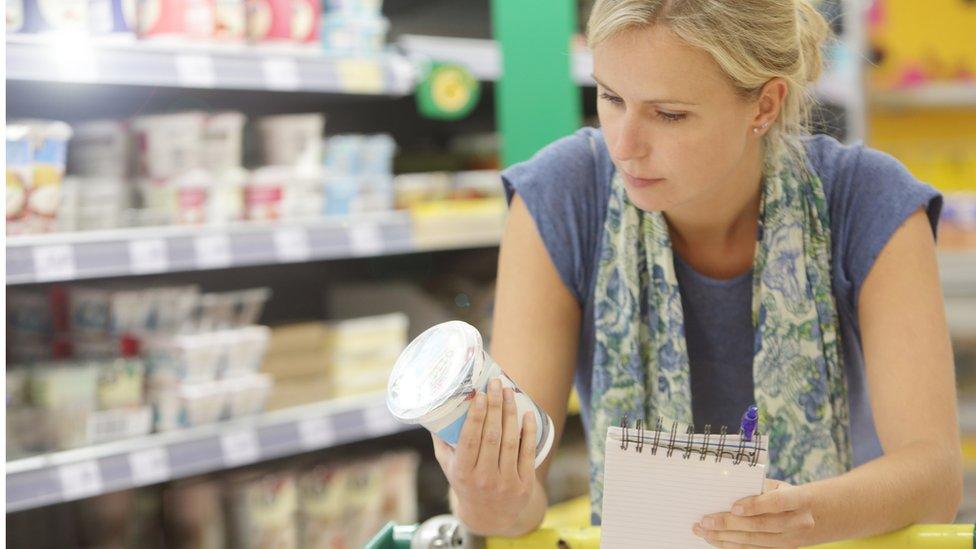 Woman looks at yoghurt pot