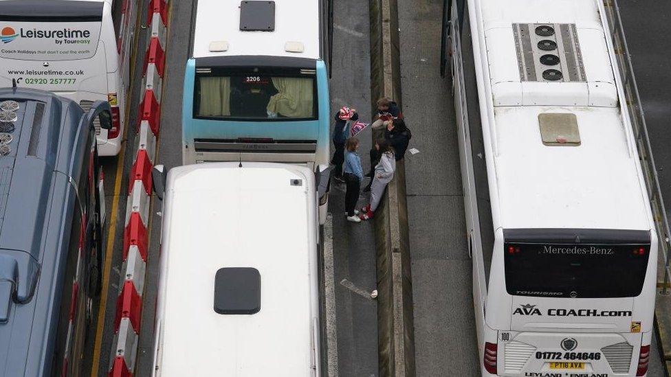 A group waits next to a coach