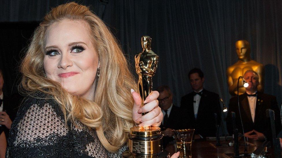 Adele holding an Oscar award