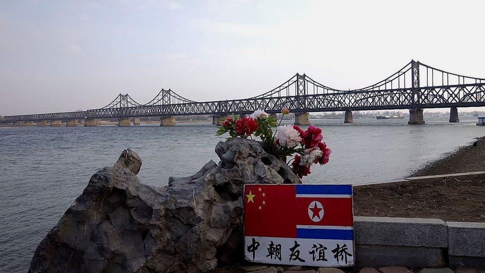 A sign displaying the Chinese (L) and North Korean (R) flags is pictured beside the Sino-Korean Friendship Bridge which leads to the North Korean town of Sinuiju, on the banks of the Yalu River, in Dandong, northeastern Liaoning province