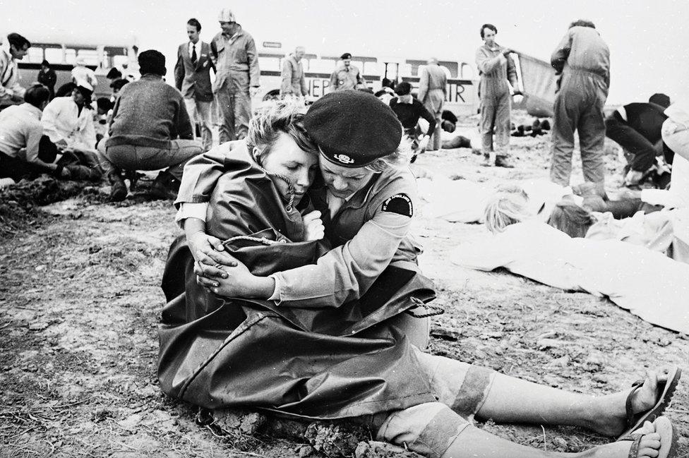 A volunteer embraces a woman wrapped in a blanket