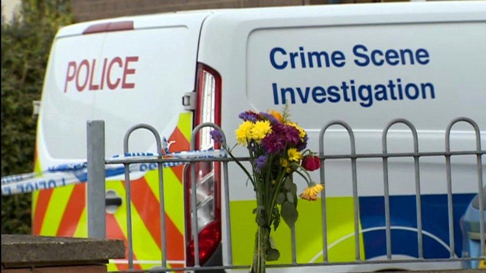 Flowers on a fence and a police van