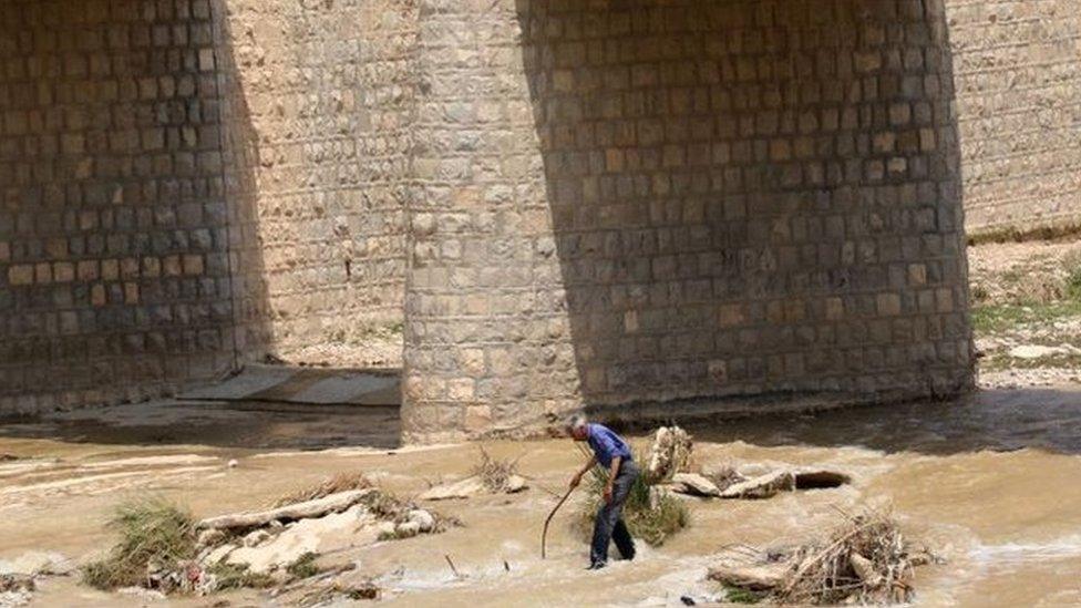 A picture obtained by AFP from the Iranian news agency Tasnim on July 23, 2022, shows people standing on a bridge above a river, after flooding caused by heavy rainfall in southern Iran's Estahban county