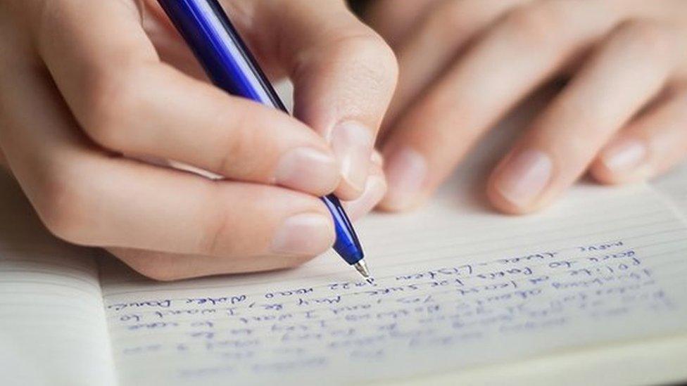 A student takes notes in print letters from a textbook