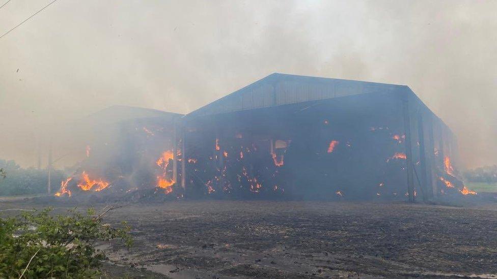 The fire at the barn on the A1120 at Pettaugh, Suffolk, the barn is well alight with flames and there is smoke rising above it