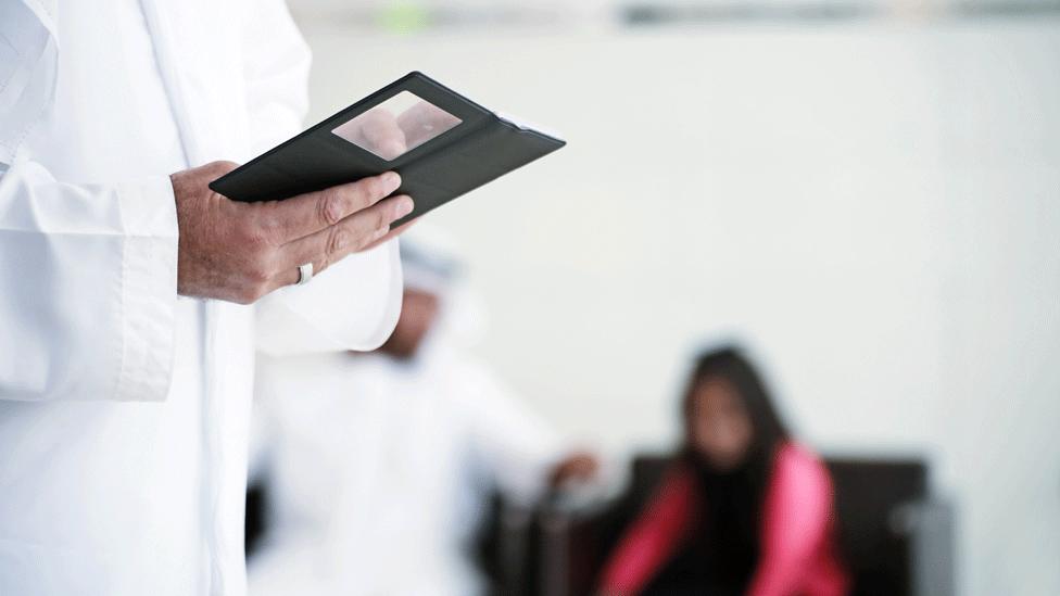 Saudi man with phone, woman in background