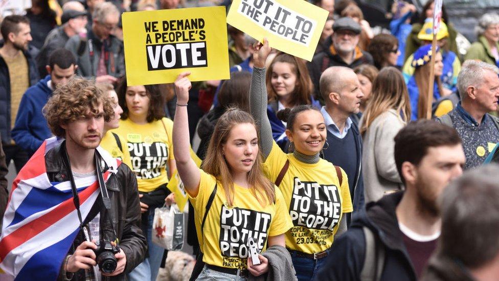 Youg people walk in the march holding "We demand a people's vote" placards