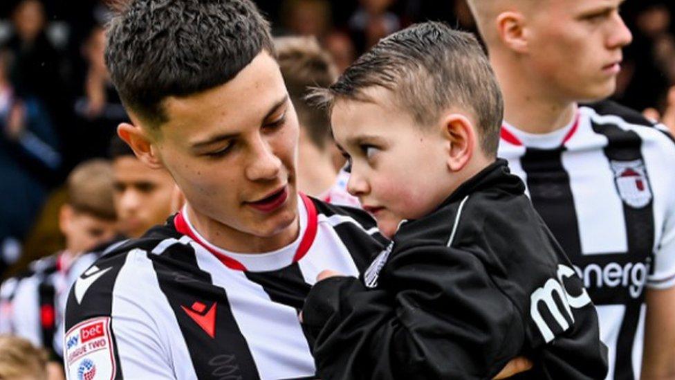 Mariners midfielder Alex Hunt carrying Reggie onto the pitch