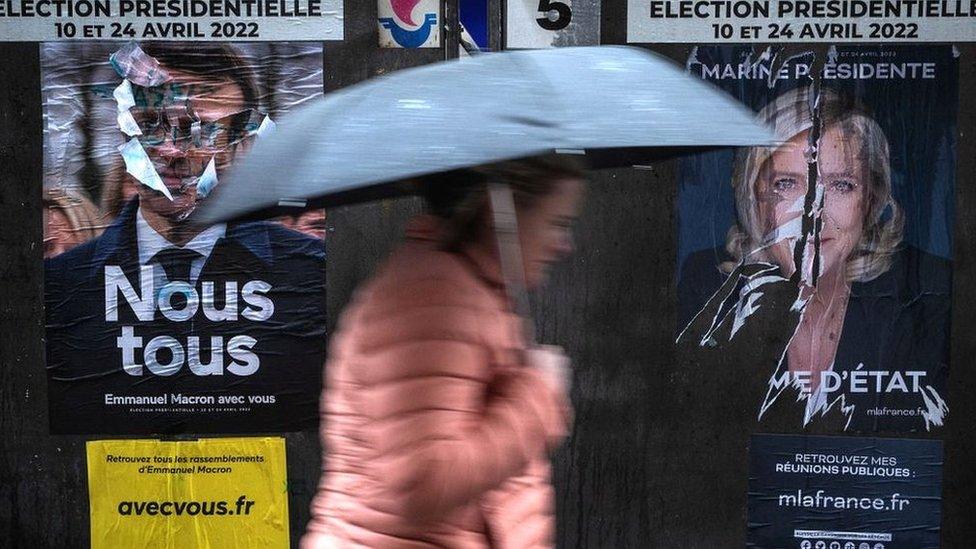 A woman walks past campaign posters in Paris on 8 April 2022