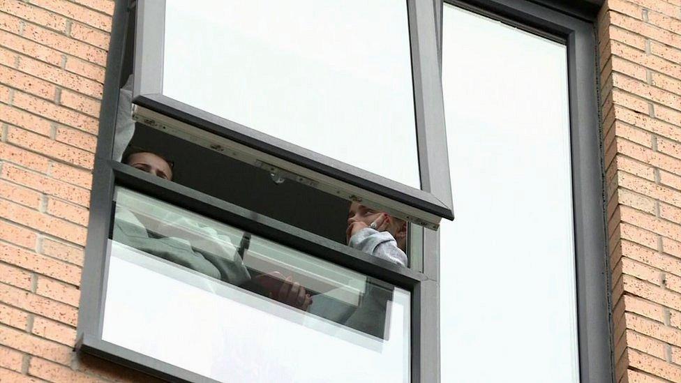 Two students look out the window of their accommodation at Manchester Metropolitan University