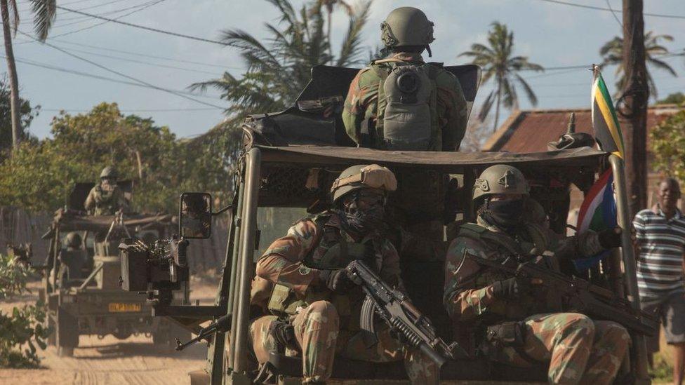 A military convoy of South Africa National Defence Forces rides along a dirt road in the Maringanha district in Pemba on 5 August 2021