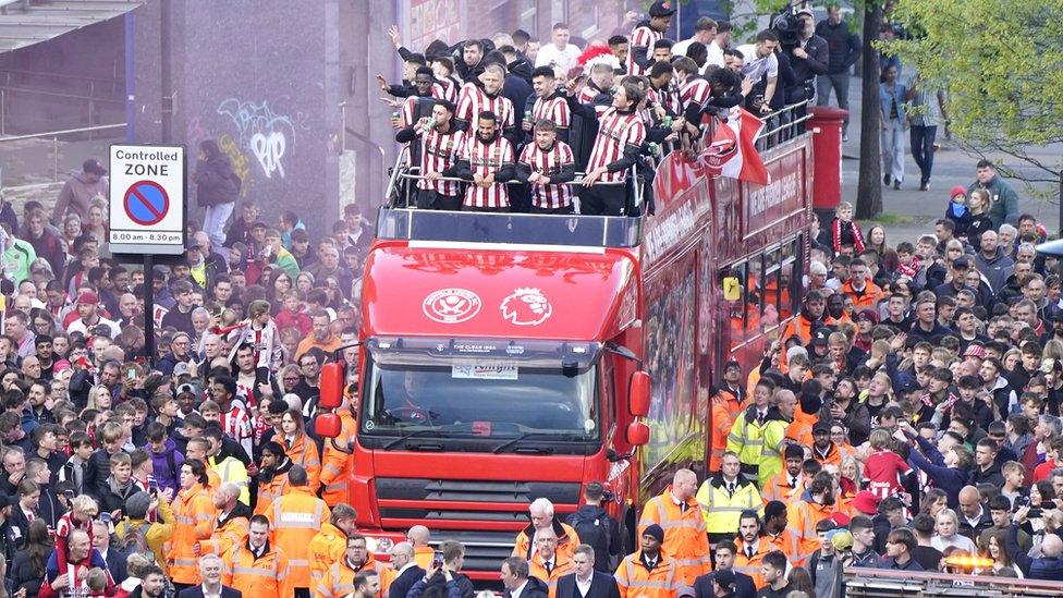 Open-top bus surrounded by fans