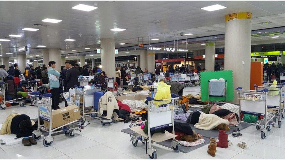 A photo taken with a smart phone camera shows passengers sleeping in a departure hall at Jeju International Airport, in Jeju, South Korea, early 25 January 2016