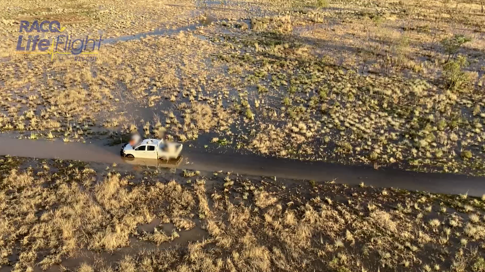 Aerial shot of the father and son sitting on top of their stranded vehicle