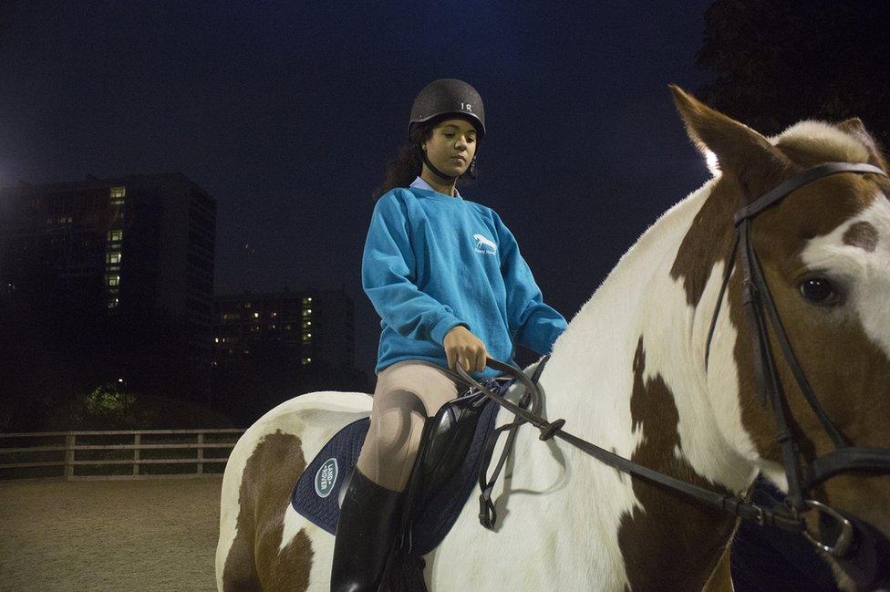 A young woman rides a horse at night