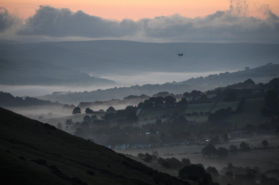 Helicopter flies in over misty valley