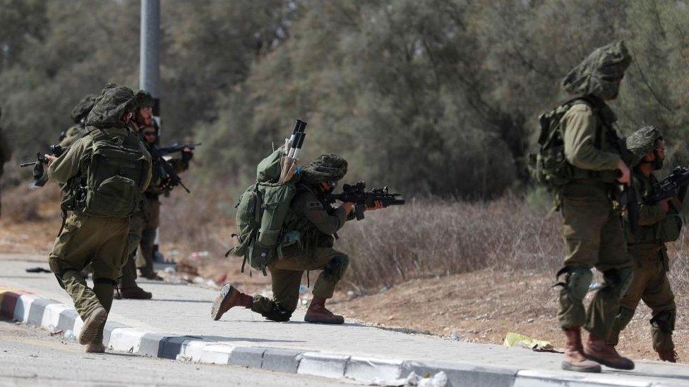 Israeli soldiers take position next to Kfar Aza kibbutz near the border with Gaza, 10 October 2023