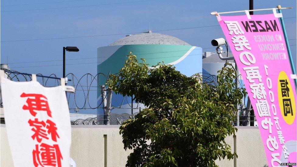 A nuclear reactor building of the Kyushu Electric Power Sendai nuclear power plant is seen between banners against the restarting of the nuclear reactor in Satsumasendai, Kagoshima prefecture, on Japan's southern island of Kyushu on 11 August 2015