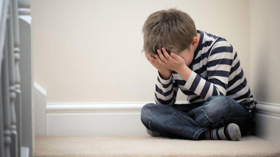 File photo of boy on stairs with head in hands.