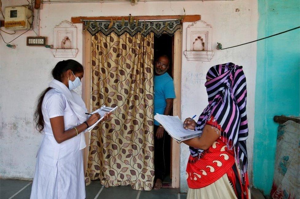 Health workers collect personal data from a man as they prepare a list during a door-to-door survey for the first shot of COVID-19 vaccine for people above 50 years of age and those with comorbidities, in a village on the outskirts of Ahmedabad, India, December 14, 2020.