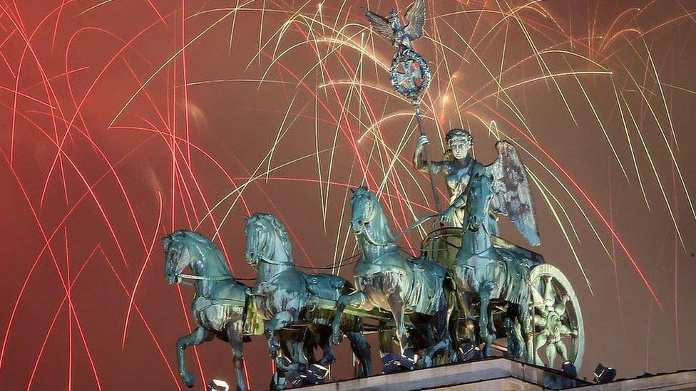 Fireworks explode behind the Quadriga statue atop the Brandenburg Gate on January 1, 2016 in Berlin,