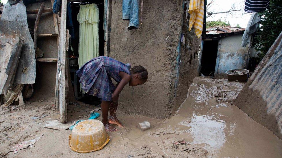 A girl washes mud from her feet after Hurricane Matthew passed in Les Cayes, Haiti